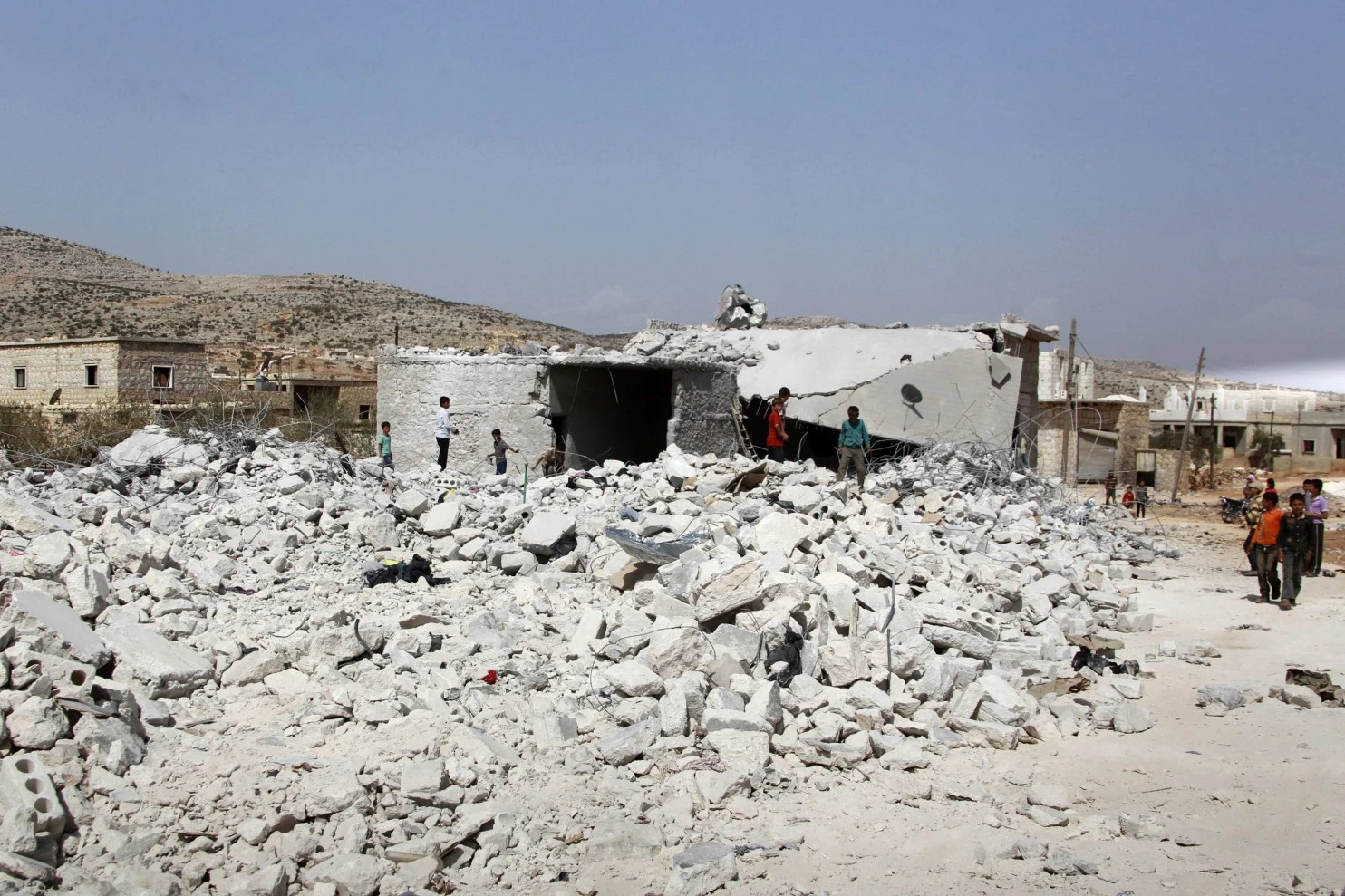 Становници сиријске провинције Идлиб (северозапад, уз границу са Турском) посматрају зграду уништену 24. септембра бомбардовањем из ваздуха. САД и њихови арапски савезници отворили су нови фронт у борби са милитантима Исламске Државе Сирије и Ирака (ИСИС) (Амар Абдула/Ројтерс)