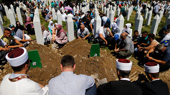 People sit around graves and tombstones at the Memorial Center Potocari, near Srebrenica, Bosnia and Herzegovina July 11, 2015 (Reuters / Antonio Bronic)